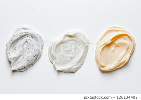 Three textured facial cream swatches in varying shades displayed on a white surface, ideal for representing beauty and skincare products. 126134492