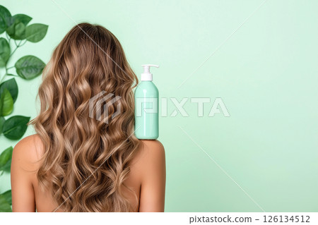 A woman showcasing her lustrous, wavy hair demonstrates a haircare product's versatility. The blue shampoo bottle on her shoulder emphasizes beauty, radiance, and healthy hair. Self-care and grooming. 126134512