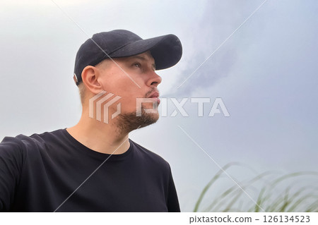 man exhales smoke from vape against fog and smog in nature 126134523
