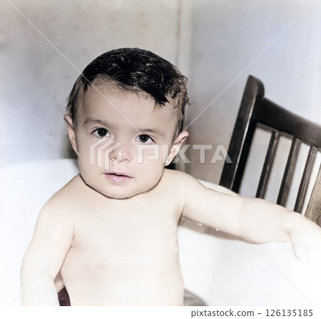 Vintage portrait of a baby girl bathing in a basin. The child is looking very attentively. Retro photo from 1994. Vintage portrait of a baby girl bathing in a basin. The child is looking very attentively. Retro photo from 1994. 126135185