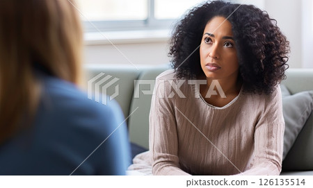Photo of a young African American woman at an appointment with a psychologist. The psychotherapist listens carefully to the patient’s story. 126135514