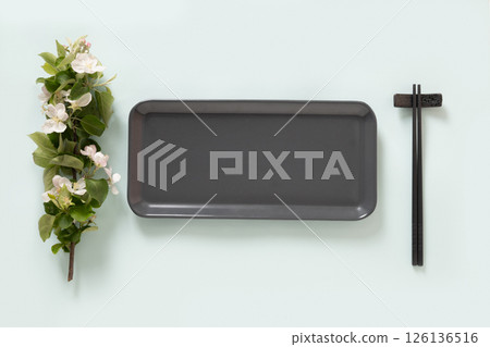 Empty rectangular gray plate for asian food with black chopsticks on blue background surface with spring branches. Asian style. View from above. Copy space. Japanese food concept. 126136516