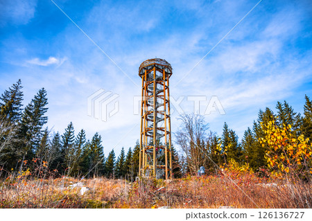 Svetly vrch lookout tower stands tall amidst vibrant autumn foliage in Albrechtice. The clear sky highlights the scenic beauty of the surrounding Jizera Mountains. 126136727