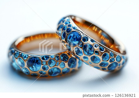 Luxurious pair of wedding rings with blue stones on a white background. Rococo-Renaissance style. 126136921