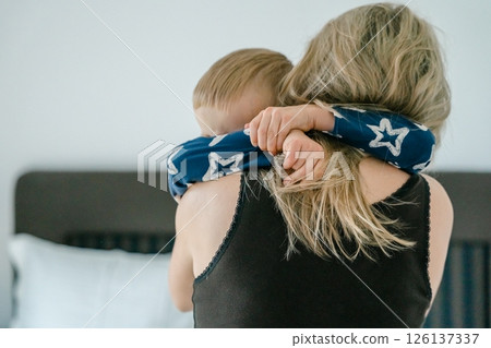 son in his pajamas in the morning hugs his mom hard around the neck. . High quality photo 126137337