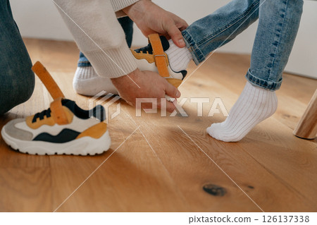 Dad slowly pulls down and pulls the white socks off the baby's feet. High quality photo 126137338