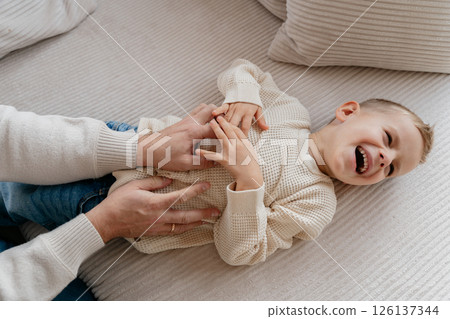 Close-up of a 4-year-old boy's face laughing from tickling his dad at home on the couch. High quality photo 126137344