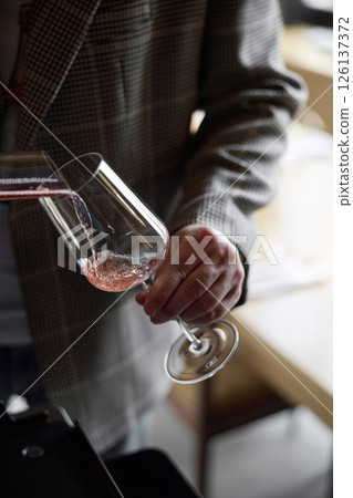 Champagne tasting, The sommelier pours sparkling wine from the decanter into a beautiful glass, Wine glasses are on the table, stylish table setting, sparkling wine bubbles 126137372