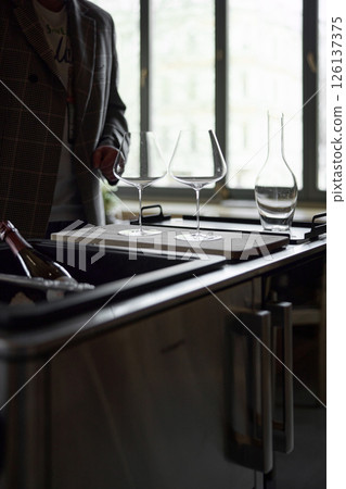 Clean wine glasses and decanter are on the table of a special wine cabinet, stylish table setting, ice, light from window, decoder and degasser 126137375