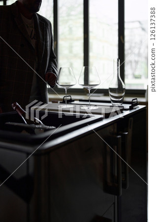 Clean wine glasses and decanter are on the table of a special wine cabinet, stylish table setting, ice, light from window, decoder and degasser 126137388
