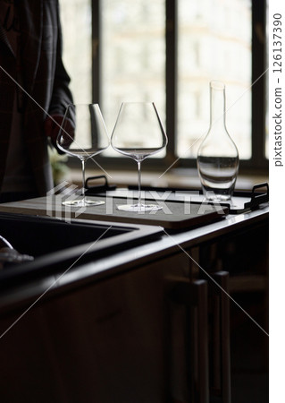 Clean wine glasses and decanter are on the table of a special wine cabinet, stylish table setting, ice, light from window, decoder and degasser 126137390