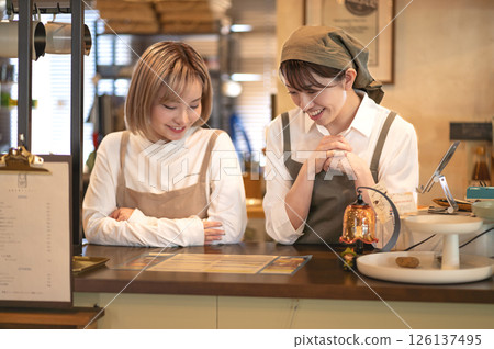 Two female baristas checking the menu at the counter Two female baristas checking the menu at the counter 126137495