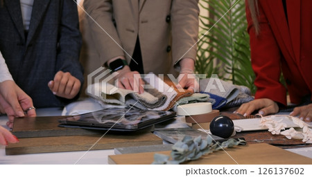Interior design professionals collaborating at table, reviewing wood, fabric, and tile samples while planning comprehensive renovation strategy. Selection of materials for interior design 126137602