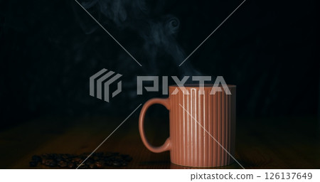 Steaming coffee mug surrounded by scattered beans, coffee evoking rich aromatic warmth, coffee inviting cozy moments and bold flavor, perfect for beverage advertising and lifestyle visuals. 126137649