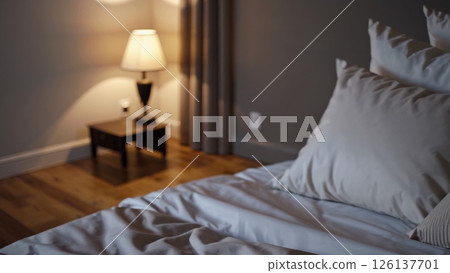 Soft light illuminates an unmade bed, inviting guests to relax in the cozy ambiance of a hotel room, creating a sense of tranquility and rest 126137701