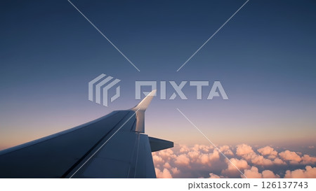 Airplane wing soaring through a beautiful sunset sky, with fluffy pink clouds stretching out below, creating a serene and picturesque aerial view 126137743
