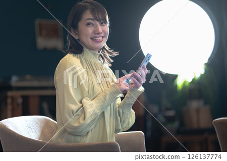 Young woman with smartphone in a coffee shop with round windows 126137774