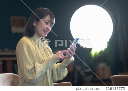 Young woman with smartphone in a coffee shop with round windows 126137775