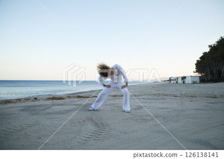 Girl in White Dancing Hip Hop on a Quiet Beach at Sundown 126138141