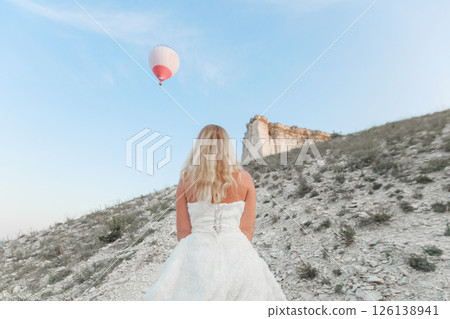 a woman in a white dress, a bride on a mountain with a blue sky. Beautiful nature, freedom, enjoyment of life. High quality photo 126138941
