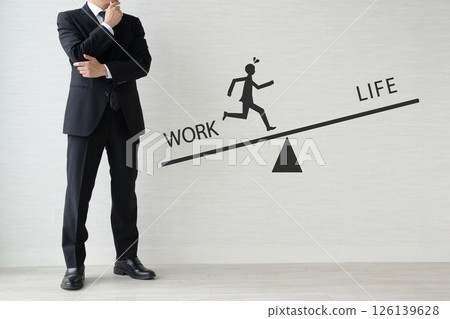 Businessman thinking about work-life balance leaning towards work Businessman thinking about work-life balance leaning towards work 126139628