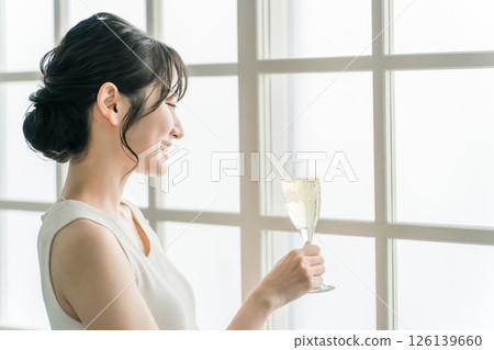 A woman who drinks champagne, carbonated water, and carbonated drinks during the day at home 126139660