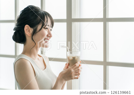 Smiling asian woman drinking cafe au lait at home in the morning 126139661