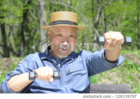 Old man with a beard doing strength training with dumbbells outdoors Old man with a beard doing strength training with dumbbells outdoors 126139787