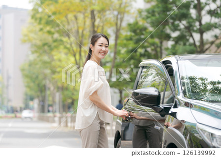 一位年輕的女士從車上下來 126139992