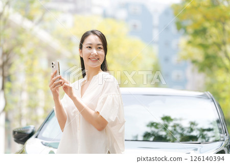 一名女子在車前看著她的智慧型手機 126140394