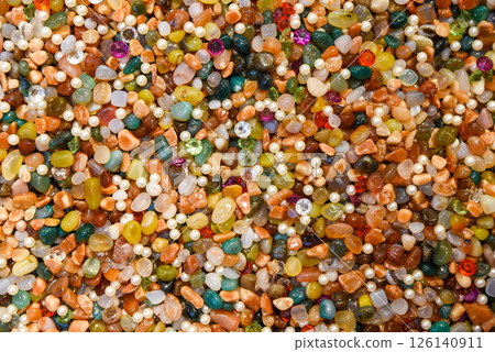 Colorful background of assorted polished gemstones, pearls, and crystals. Bright, vibrant texture of mixed natural stones and beads in various shapes and colors, ideal for abstract backdrop 126140911