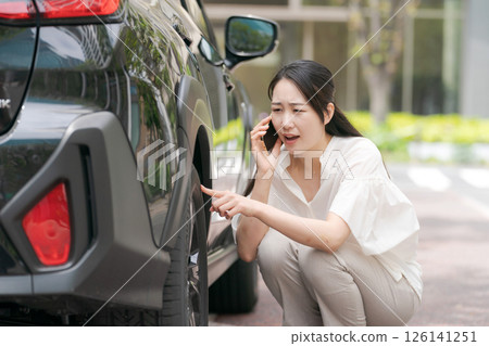 Young woman checking tire trouble Young woman checking tire trouble 126141251
