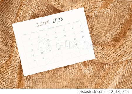 June 2025 calendar card on golden color textile. 126141703