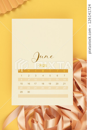 June 2025 calendar page with ribbon on yellow background. June 2025 calendar page with ribbon on yellow background. 126141724