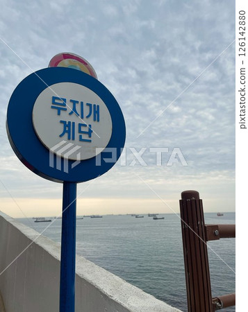A sign and seascape of the "Mujigae Stairs" along the sea in Busan, South Korea 126142880