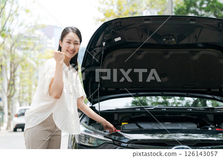 Woman opening the hood of a car Woman opening the hood of a car 126143057