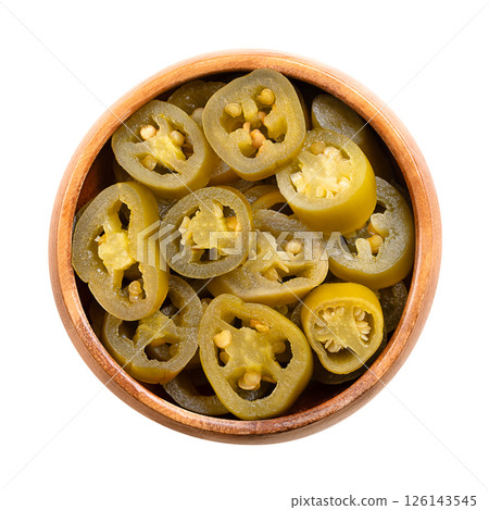 Pickled green jalapeno slices in a wooden bowl. Medium-sized hot, green chili peppers, cut into cross sections, pasteurized and preserved in a salted vinegar brine. Isolated, from above, food photo. 126143545