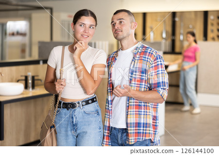 Friendly young couple looking for bathroom fixtures in showroom 126144100