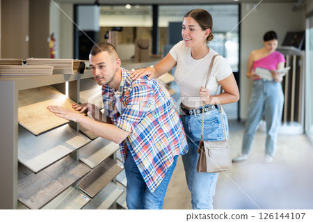 Young married couple chooses laminate flooring together in hardware store Young married couple chooses laminate flooring together in hardware store 126144107