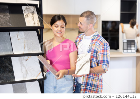 Husband and wife discussing the color of ceramic tiles for the bathroom in hardware store 126144112