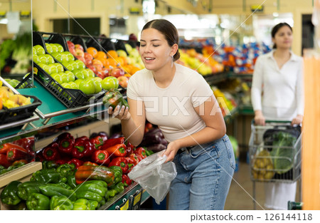 Young woman shopper chooses bell pepper in supermarket Young woman shopper chooses bell pepper in supermarket 126144118