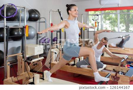 Sportive young girl training her arms and legs on reformer device 126144167