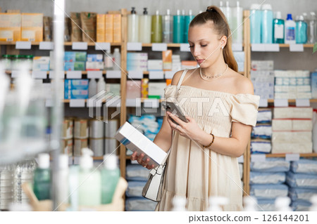 Woman in a beautiful dress scans a package of cream Woman in a beautiful dress scans a package of cream 126144201