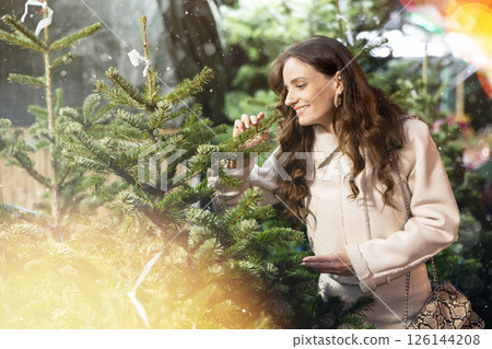 Young woman looking for fresh Christmas tree on outdoor market 126144208