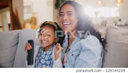 Mom, girl and happy for watching tv on couch with remote control for movie, hug or bonding with love. Child, mother and daughter with smile, care or laugh on sofa for streaming film in family home 126144209