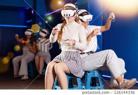 Female friends competing in two-on-two virtual reality game 126144336