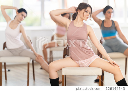 Young female dancer practicing lap dance on chair in studio 126144343