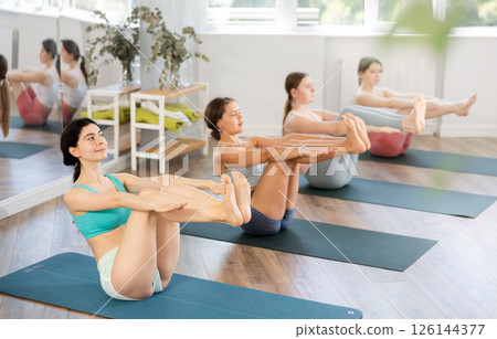 Young woman balancing in boat pose Navasana in yoga class 126144377