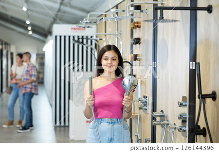 Young girl choosing a shower head in hardware store 126144396