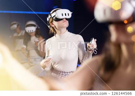 Expressive girl in VR goggles having fun in virtual reality room 126144566